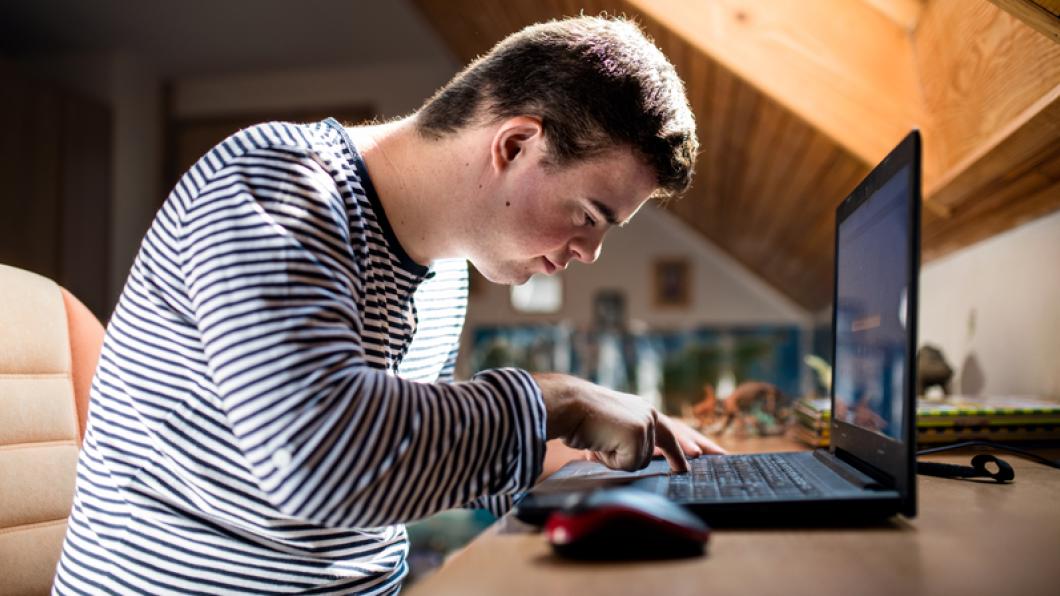 Young man bends over typing at computer