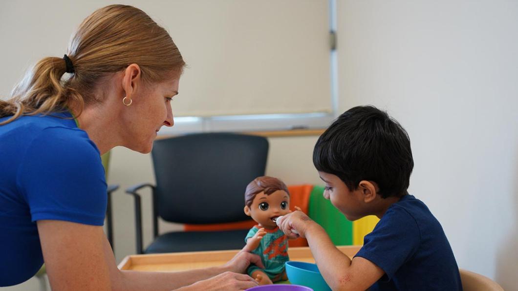 An adult is playing toys with a young child