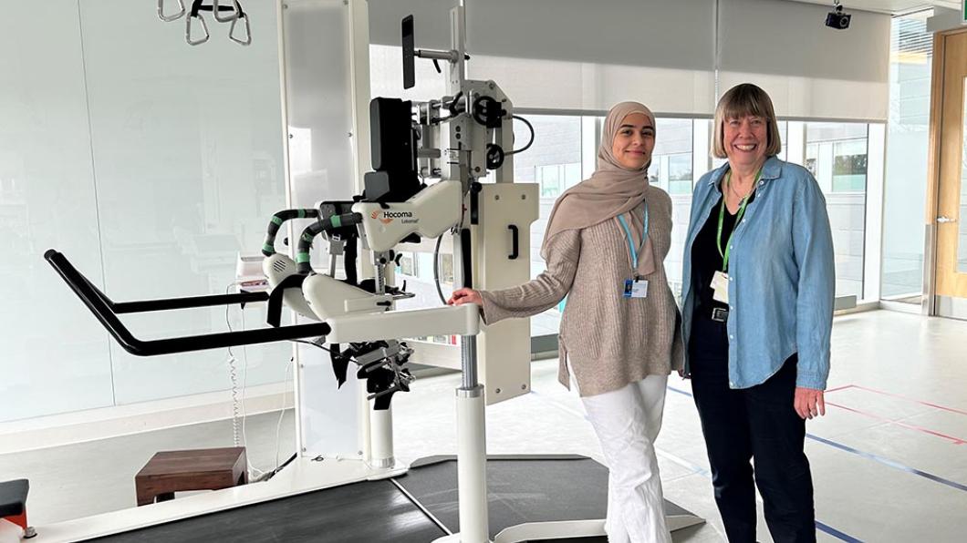 Two women stand in front of a robotic treadmill