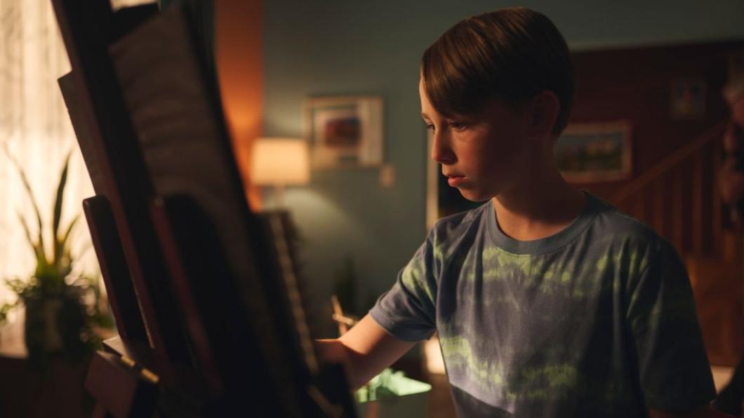 Boy sits at easel drawing