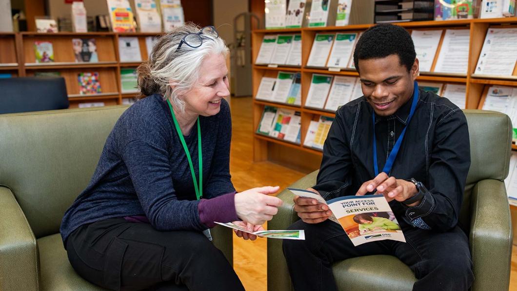 Two adults reading leaflets in a library setting