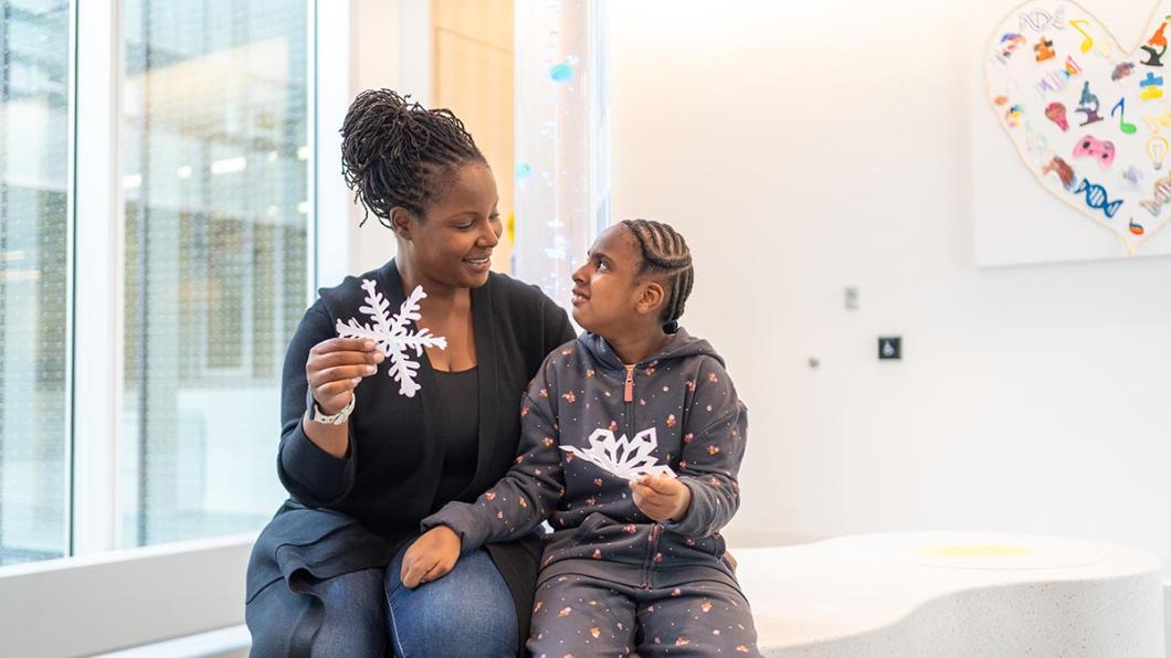 An adult with a child holding some holidays stars