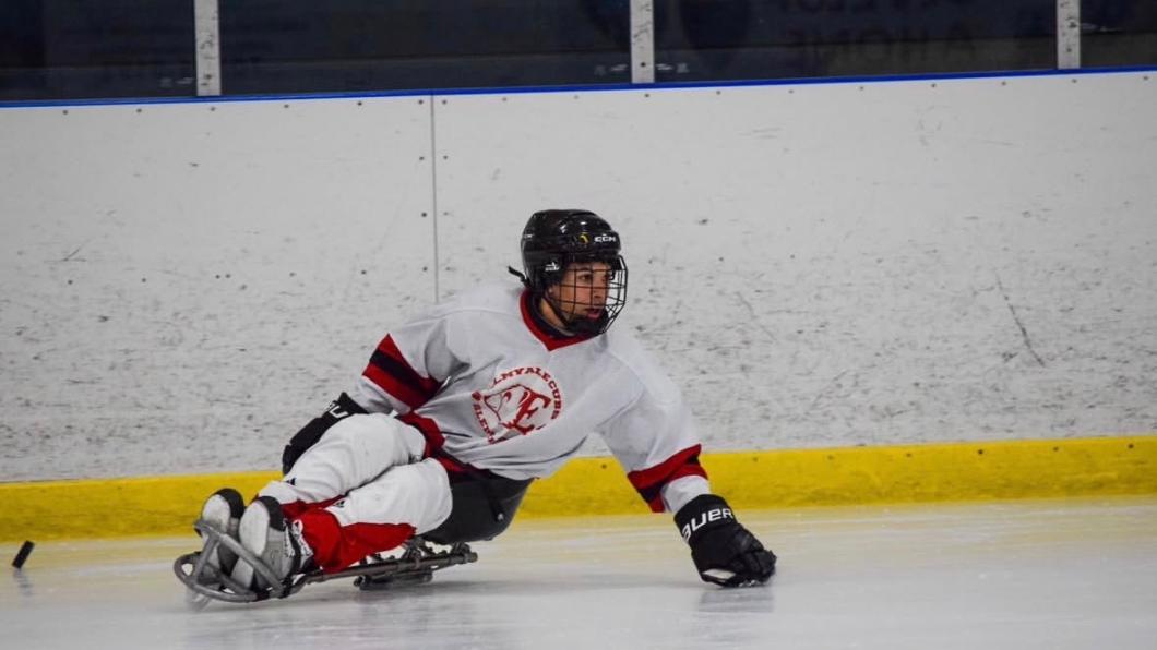 A young boy plays sledge hockey.
