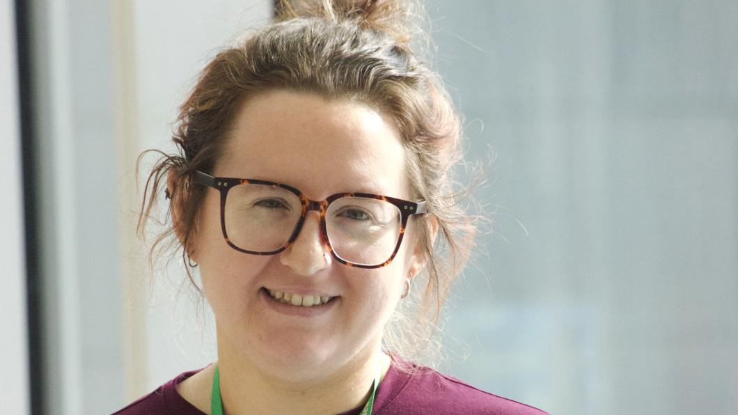 Woman with glasses and brown hair in updo smiles