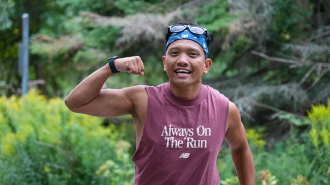 A man runs and flexes his bicep