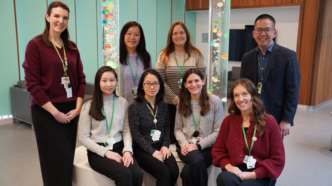 group of adults, some sitting and others standing, in a room with bubble towers in the background