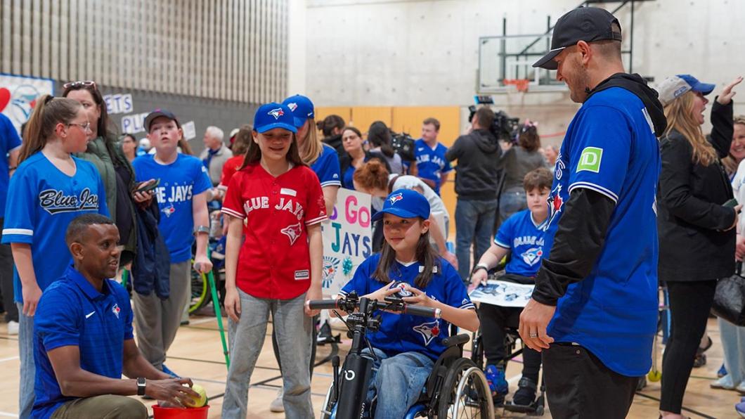 A kid on wheelchair accompany with some adults in a basketball courtyard