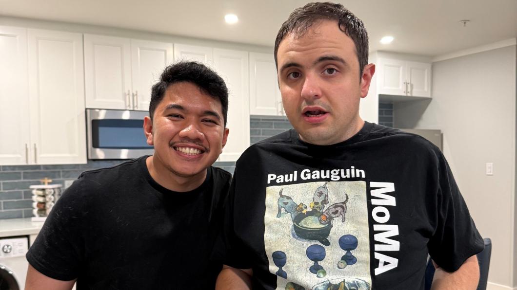 Two young men with kitchen behind them