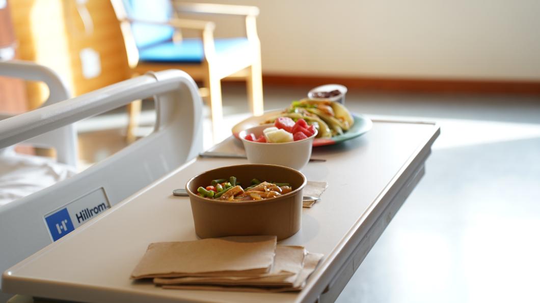 Bowls of food placed on a table in a hospital room.