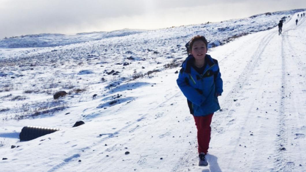 a boy walking on snow covered ground