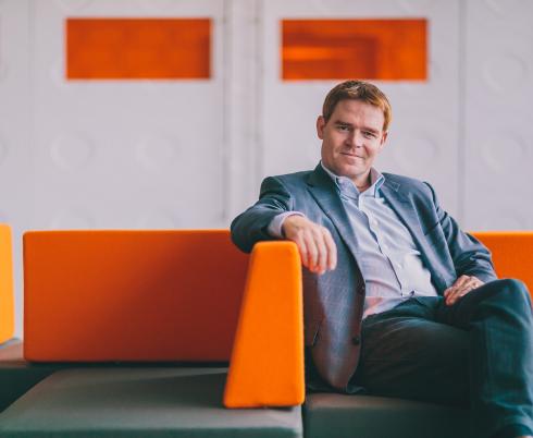 Jason Smith sitting on an orange and green couch