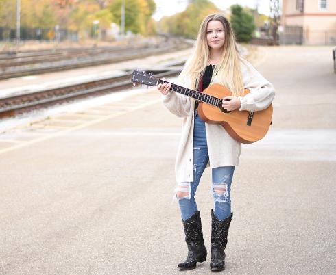 Em Jordan holding her guitar.