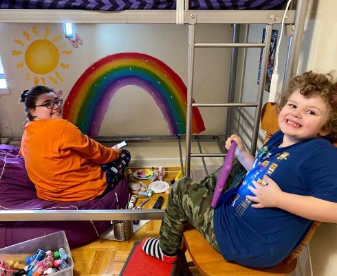 children sitting in front of a painting of a rainbow