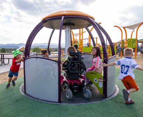 children playing on accessible merry go round