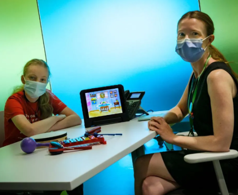 Two students sit at a table with a tablet 
