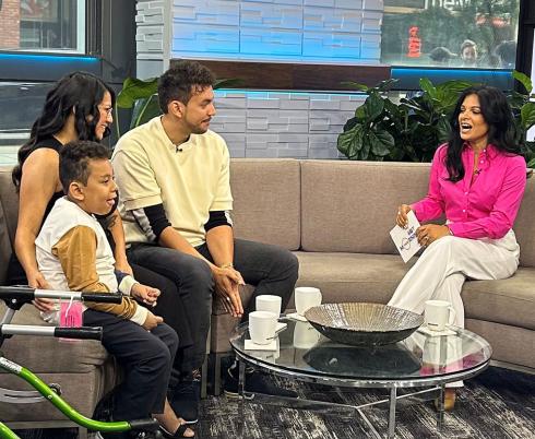 A TV shows with 3 adults and a child with a walker on the side.