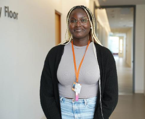 A headshot of Bisola. She is wearing a grey t-shirt and black cardigan.