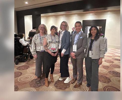 A group photo of 5 people in a conference