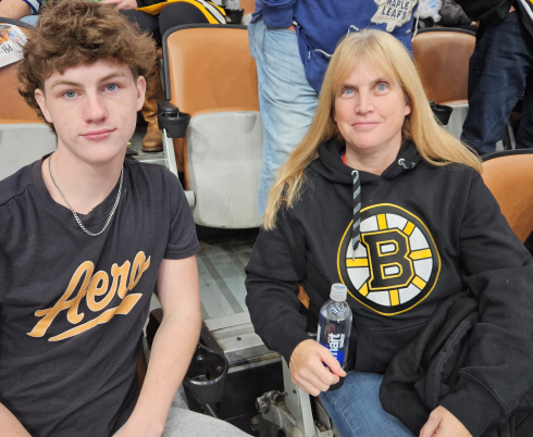 A teenage boy and his mom sit together at a hockey game.