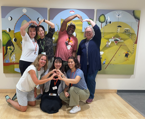 group of adults are smiling and posing for a photo against artwork in the background