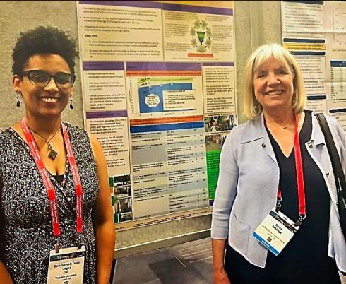 Dr. Selamesh Tsige-Legas and Dr. Darcy Fehlings stand in front of a research poster