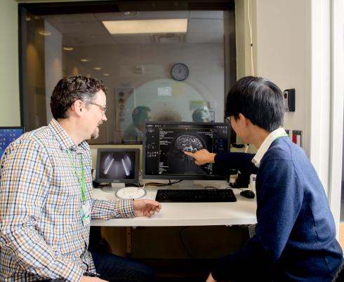 Two adults looking at an image of a brain scan on a computer screen