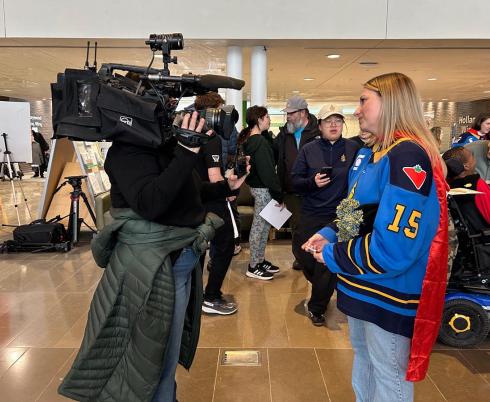 An adult is being interviewed by a camera reporter