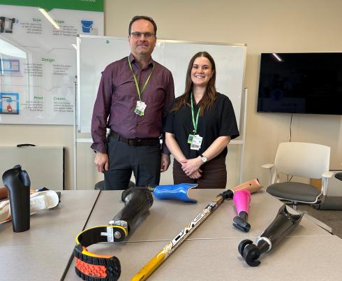 A man and a woman standing behind some tools for disabilities