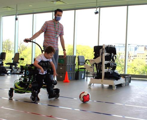 A child using the Trexo to kick a soccer ball indoors