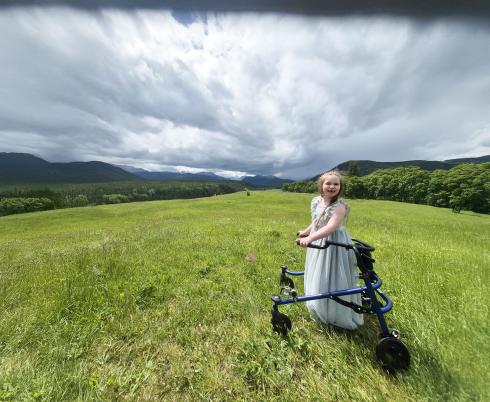 A child with walker is in the grass field