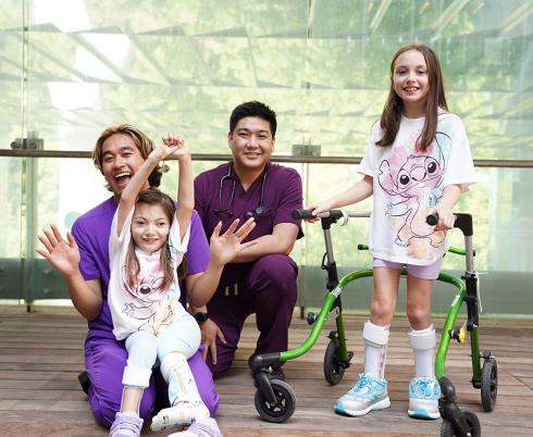 Two adults nurses are having group photos with two children patients