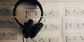 black headphones sitting atop a background of sheet music